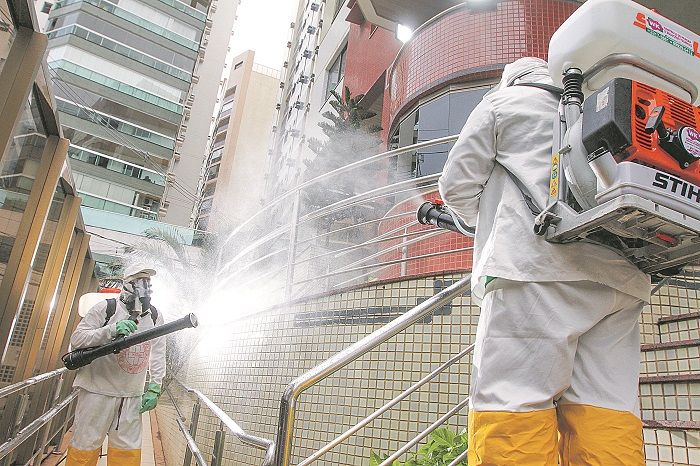 Funcionários de empresa fazem desinfecção com aparelhos especiais em áreas comuns de prédio em Vila Velha (Foto: Beto Morais/AT)