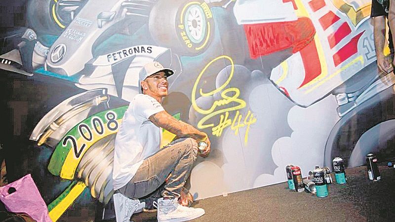 Lewis Hamilton fez questão de pegar o spray e também deixar sua marca no mural feito em sua homenagem, em São Paulo (Foto: Divulgação)