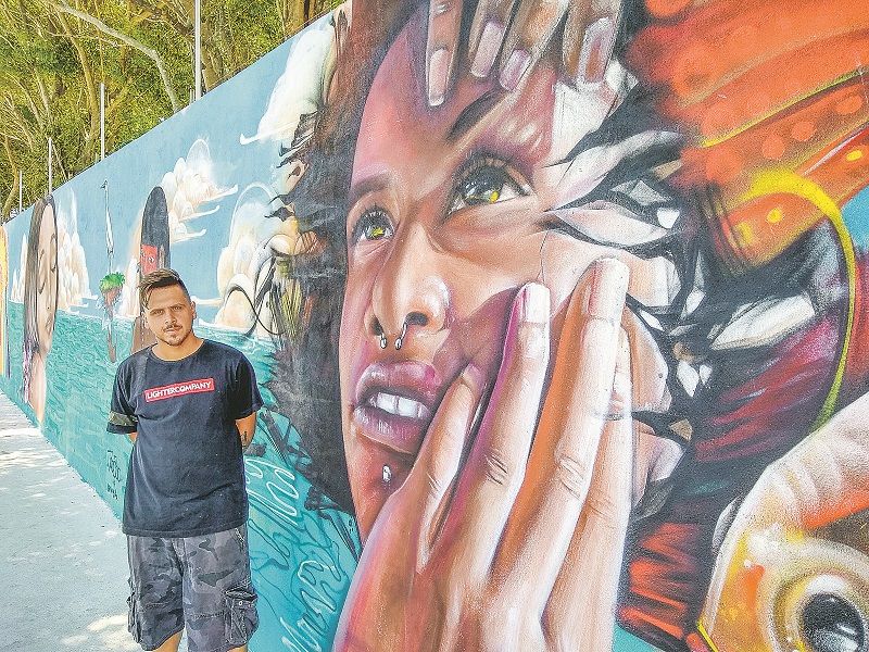 Liam Bononi ao lado de mural que fez em Guarapari. “Quero trazer reflexão para a galera que está no meio urbano” (Foto: Roberta Bourguignon)
