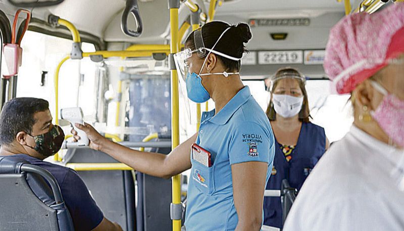 Servidora verifica temperatura de passageiro em ônibus (Foto: André Sobral/ Divulgação)