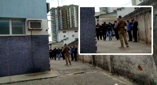 Suspeito chegou ao local escoltado por policiais e com a cabeça encapuzada (Foto: Kananda Natiely / AT)