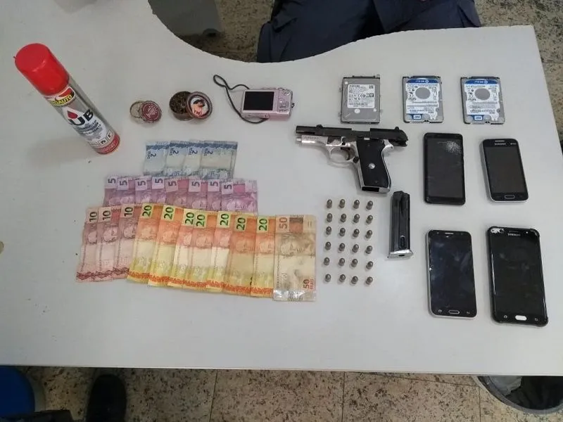Pistola, munição, celulares, dinheiro e outros objetos apreendidos na casa de Kelvin da Silva.