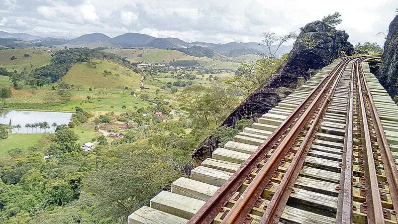 Linha férrea atravessa rios, túneis, estações centenárias, pontilhões construídos em paredões de pedra, cadeias de montanhas e muito verde