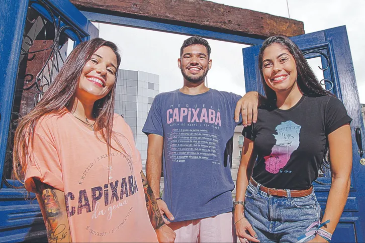 Renata, Vitor e Fernanda vestem camisas que valorizam a cultura, com frases e imagens de pontos turísticos