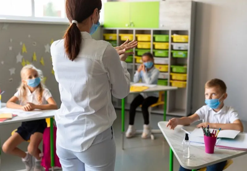 Professora com alunos na sala de aula durante a pandemia do novo coronavírus: novo normal