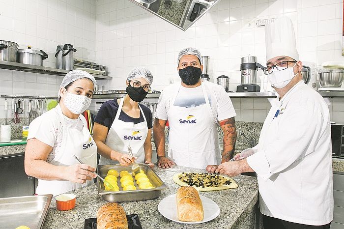 Os alunos Gilcilene Barbosa, Mônica Vargas e Thiago Norbin recebem orientação do professor Kleber Lopes sobre produção de pães e outras delícias artesanais (Foto: Dayana Souza/AT)