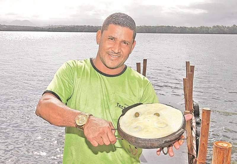 O garçom Wando Alves mostra torta capixaba preparada por restaurante da Ilha das Caieiras, em Vitória