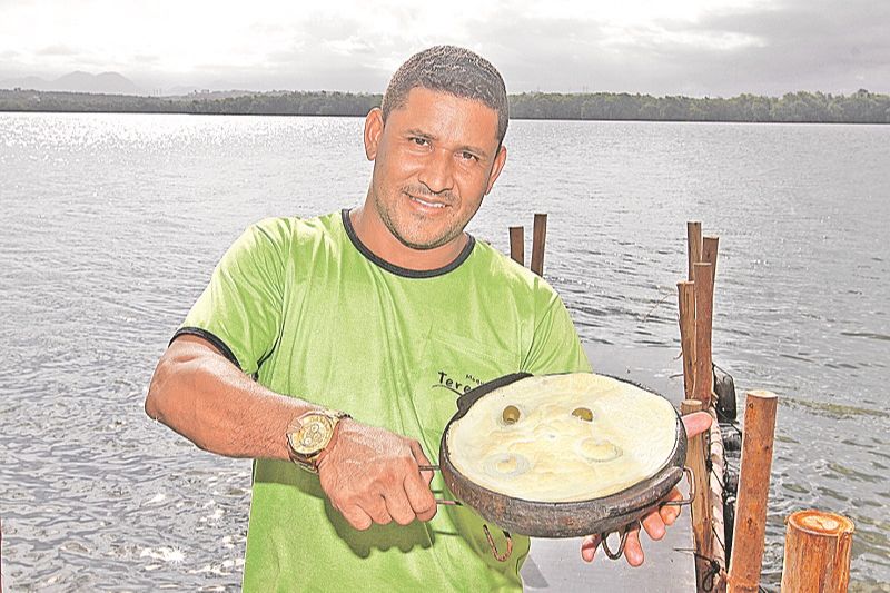 O garçom Wando Alves mostra torta capixaba preparada por restaurante da Ilha das Caieiras, em Vitória (Foto: Leone Iglesias/AT)