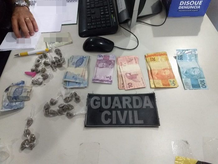 Dinheiro e drogas apreendidas com suspeitos. Agentes não localizaram o criminoso que atirou (Foto: Divulgação )