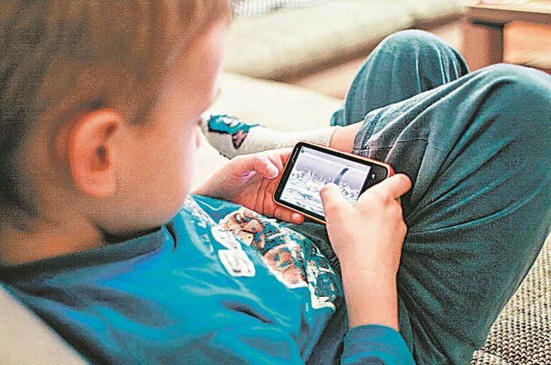 Criança usa smartphone em posição inadequada: perigo de doenças (Foto: Divulgação)