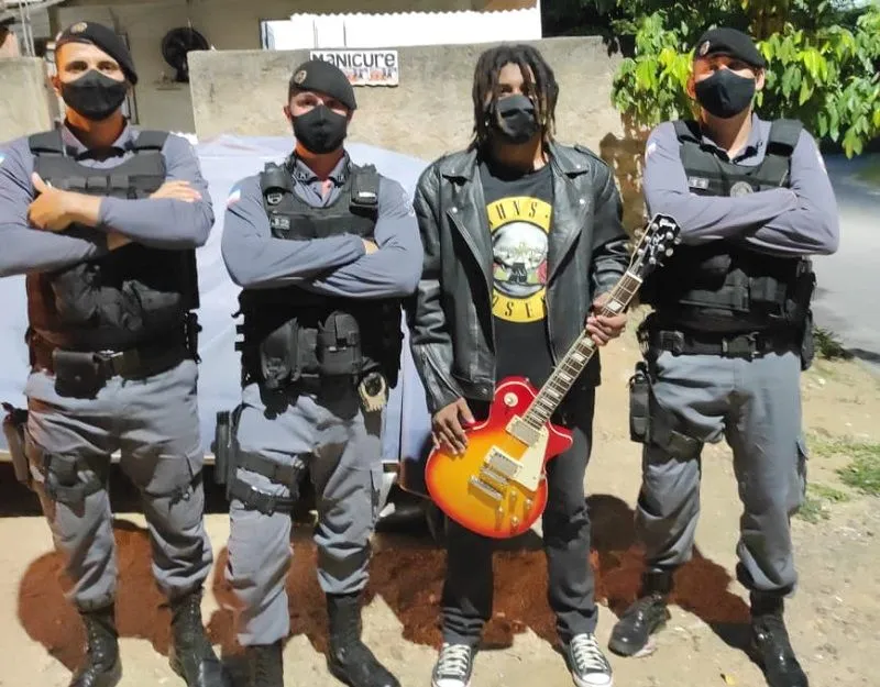 Após prender suspeito de tráfico de drogas, policial tocou clássicos do metal com guitarra do irmão do detido (no centro)