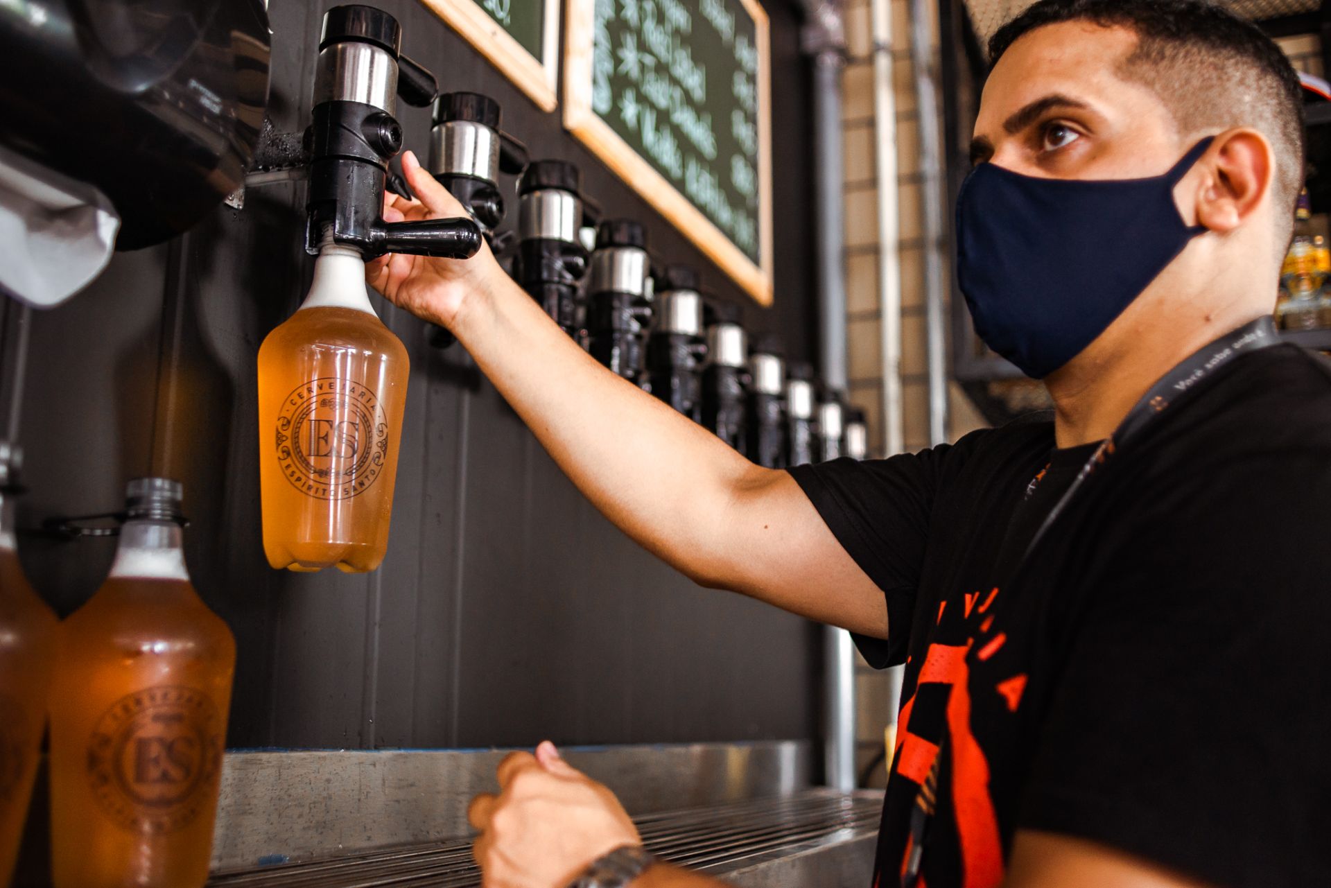 Barman enche growler com o estilo mais pedido pelo delivery, a Pilsen