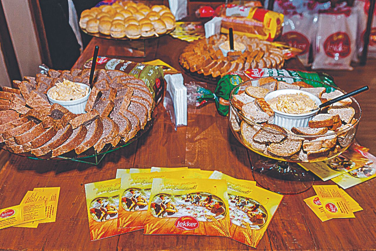 Variedade de aperitivos e sabores à mesa com as linhas de produtos Lekker, como pães de vários tipos, biscoitos e suco