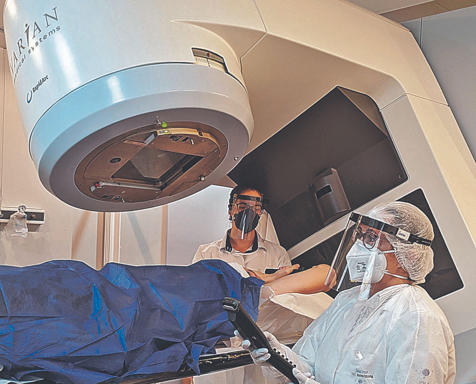 Técnicos em radioterapia preparam paciente para sessão. Diagnóstico precoce é importante para combater a doença
