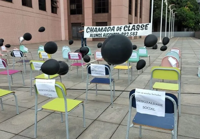 Pedindo o retorno das aulas presenciais, os manifestantes posicionaram cadeiras escolares com balões pretos, representando o luto pelo fechamento das escolas