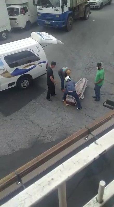 Homens tentam recolocar o caixão no veículo. (Foto: Reprodução)