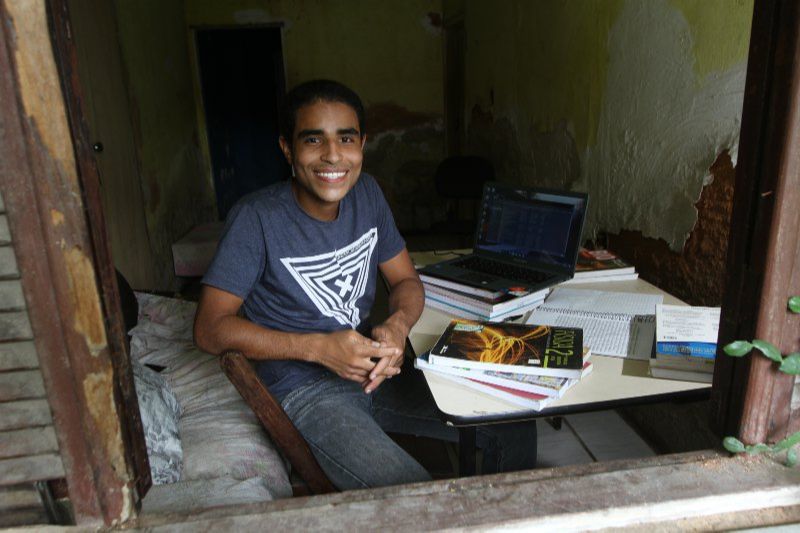Pedro Carlos em casa, com os livros e notebook que ele usa nas primeiras aulas do curso (Foto: Dayana Souza)