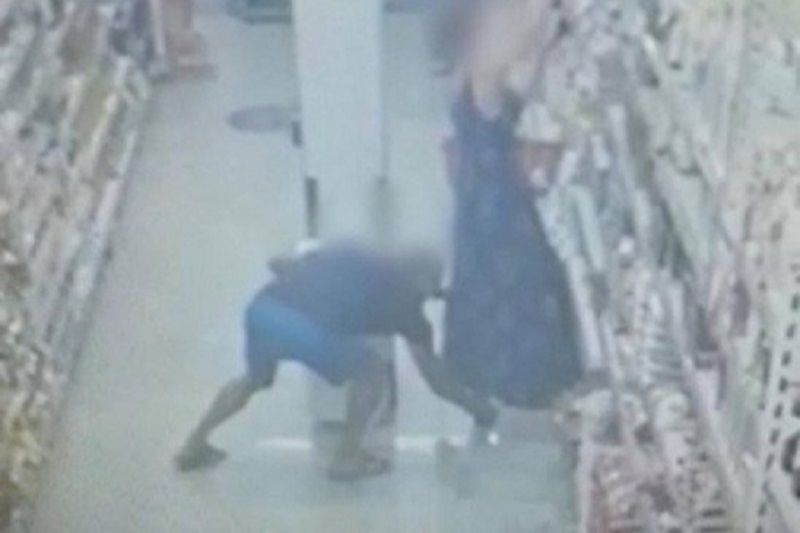 A mulher estava procurando um produto em uma prateleira alta, quando o criminoso coloca o celular por baixo do vestido longo que ela usava (Foto: Reprodução)
