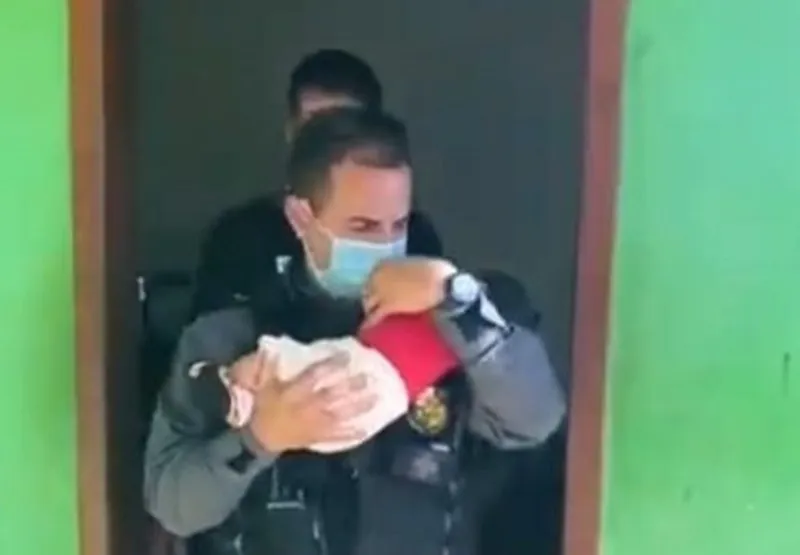 Policial carrega bebê resgatado de boca de fumo no Mato Grosso.