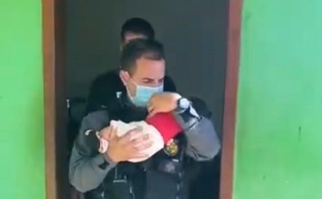 Policial carrega bebê resgatado de boca de fumo no Mato Grosso. (Foto: Divulgação)
