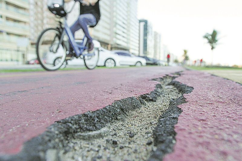 Os buracos na ciclovia da orla de Itaparica são visíveis. Na foto, pedestre desvia de um para evitar possível acidente. (Foto: Beto Morais/AT)
