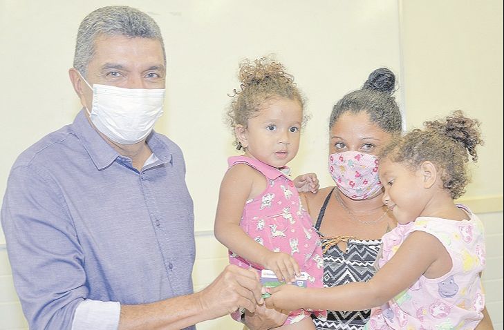 Vanessa com as filhas gêmeas Agatha e Andressa, de três anos, no colo. Elas recebem o cartão Serra Social das mãos do prefeito Sergio Vidigal. (Foto: Tom Paparazzy/Secom-PMS)