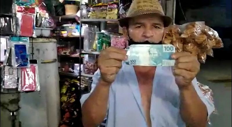 Seu José Vitor segurando a nota falsa de 100 reais (Foto: Reprodução/Leitor do Tribuna Online)