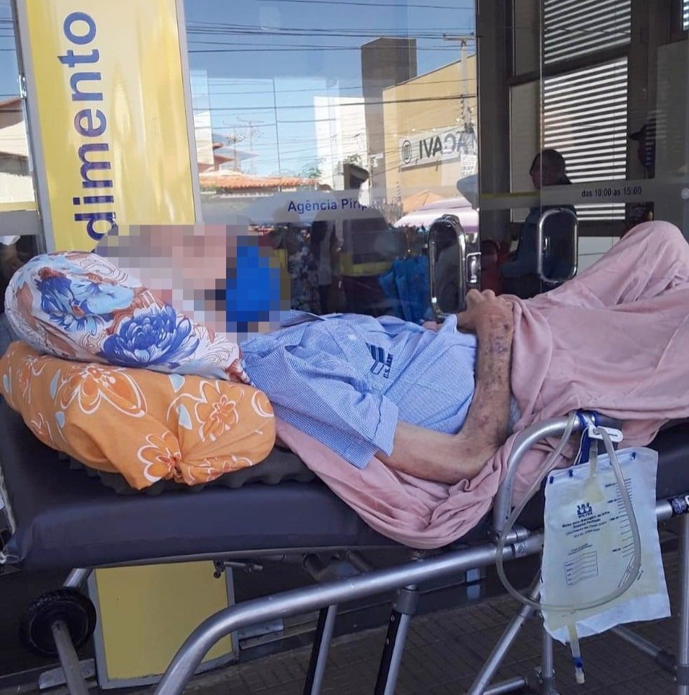 Idoso foi levado de maca para fazer prova de vida em banco (Foto: Reprodução)