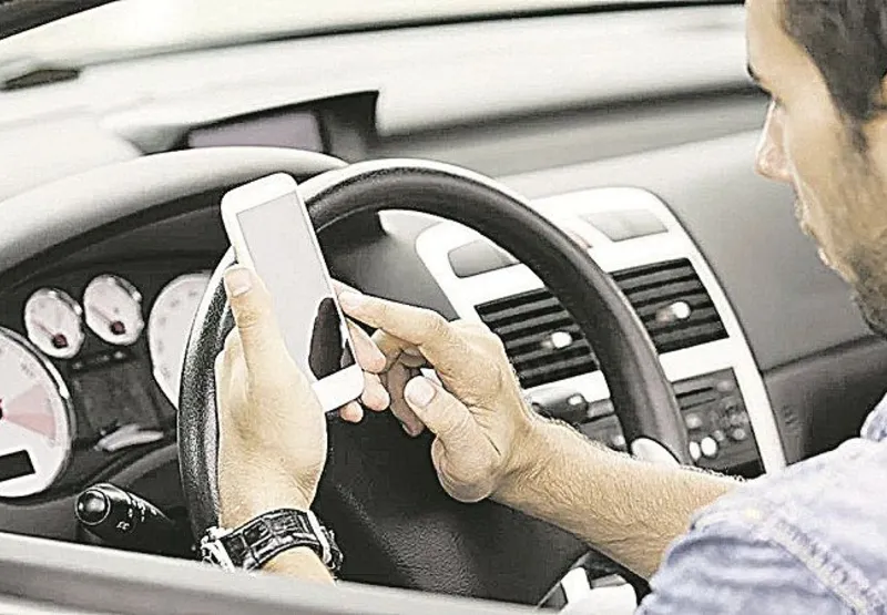 Motorista usa celular ao volante: distração põe em risco o condutor, os pedestres e quem está em outros veículos
