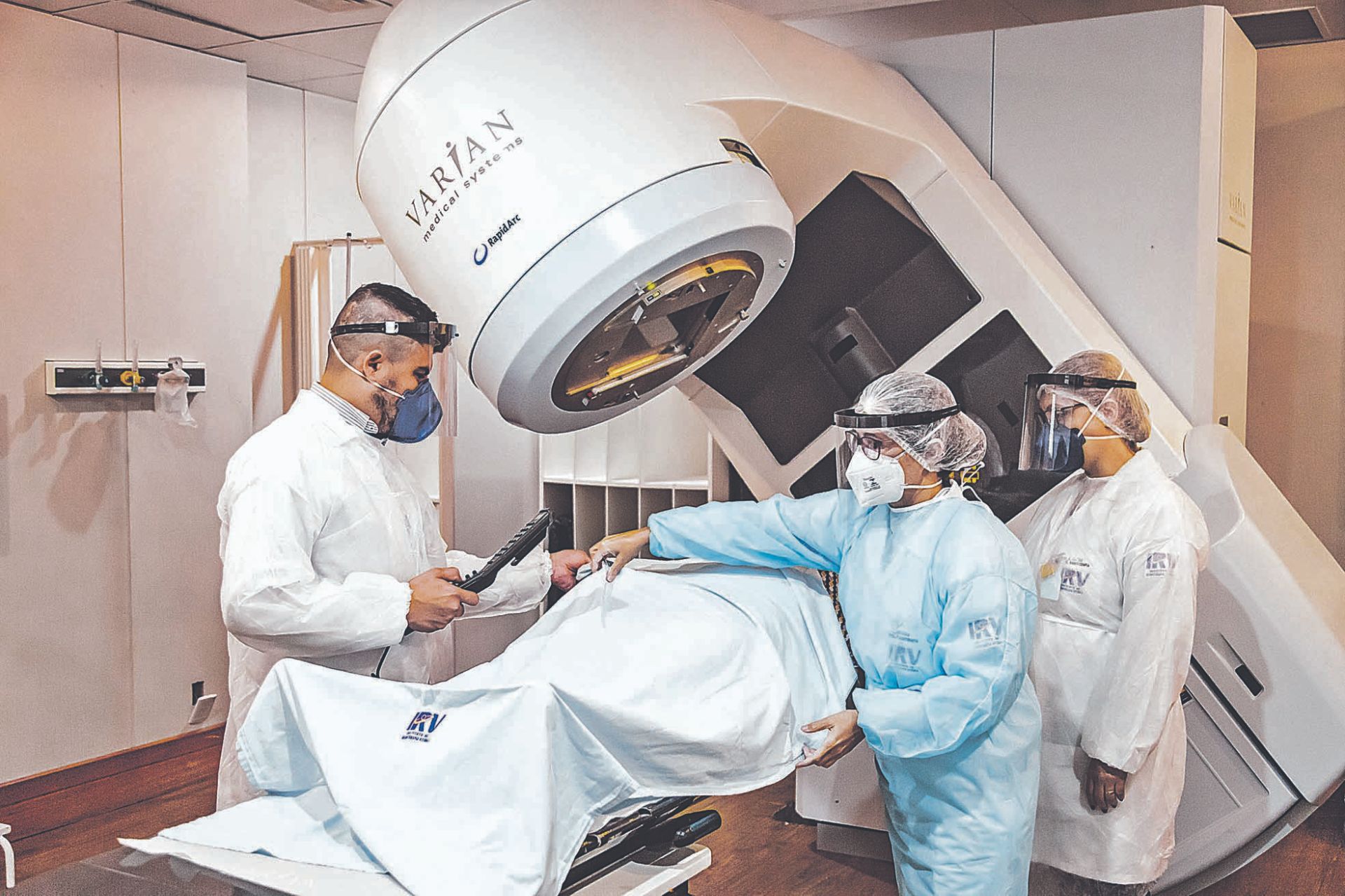 Técnicos em radioterapia preparam paciente para sessão: unidade mantém protocolos de segurança