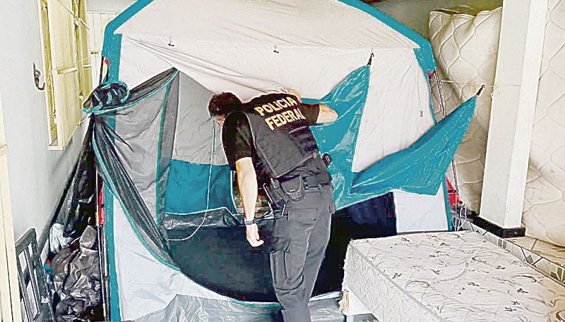 Polícia analisa local onde mineiros dormiam, com barracas em uma casa (Foto: Polícia Federal / Divulgação)